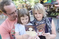 Stefanie und Ren� Heering schauen sich mit Tochter Laura die Erm��igungen an, die der neue Rummelpass bietet. Die Rabattkarte wird in diesem Jahr erstmals zum Stadtparkfest angeboten. 