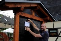 Weit und breit einmalig. Wirt Frank Wirth nimmt heute das Schwarze Brett an der Oberreichenbacher "Scheune" in Betrieb. Gebaut hat's Zimmmerer-Nachbar Uwe Planitzer, Tilo B�ttiger deckte das Dach.