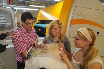 <p class="artikelinhalt">Die Frankenberger Firma Color Textil tüftelt ständig an neuen Produkten. Studenten wie Karolin Runst und Claudia Dallwitz (r.), hier mit Frank Schlosser an der Druckmaschine, haben ein großes Betätigungsfeld.</p>