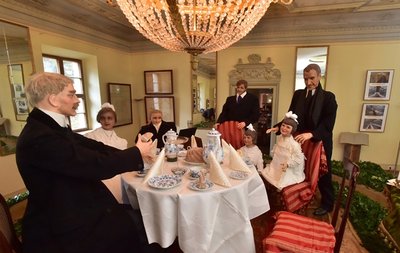 <p>
	Zudem haben die Mitarbeiter der Kameliensammlung mit vielen Ideen Szenen aus dem Leben des letzten Sachsenkönigs Friedrich August III nachgestaltet. Dort sitzt er mit seinen fünf Kindern am Kaffeetisch. Seine Gemahlin Louise von Toscana, Kronprinzessin von Sachsen, entfloh schon zwei Jahre vor der Krönung im Jahre 1902 gemeinsam mit dem Sprachlehrer der Kinder in die Schweiz. Die Frage der kleinen Tochter an der Kaffeetafel: "Vater, derfmer die Bäbe ditschen?"</p>
