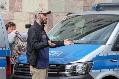 <p>Pro-Chemnitz-Chef Martin Kohlmann steht vor einer Kette aus Polizeifahrzeugen und gestikuliert in Richtung der Gegendemonstranten.</p>