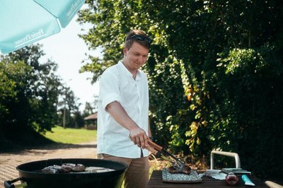 <p>Volontär Erik Anke am Grill. Nette Nachbarn vom Campingplatz haben der Redaktion das gute Stück ausgeliehen.</p>