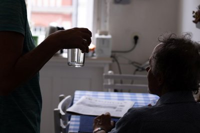 Trinken nicht vergessen: Eine Pflegerin reicht ihrem Patienten ein Glas Wasser.