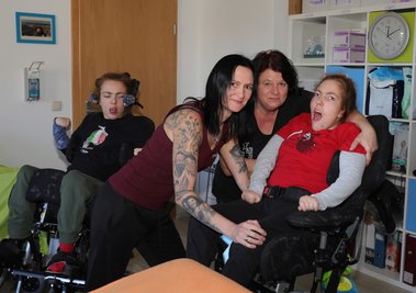 Mutter Stephanie Dittrich-Schulz (vorn links) und Heike Wagner setzen Fanny nach einer Therapiestunde in den Rolli. Im Hintergrund wartet Stella auf ihre Schwester. 