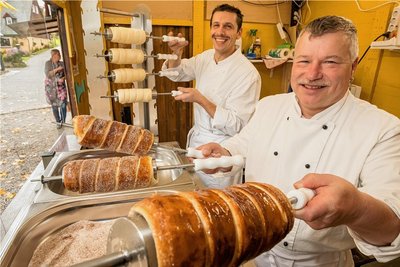 Gerd Weidner (vorn) und André Schubert backen auf dem Seiffener Sternenmarkt Baumstriezel. 