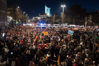 Teilnehmer stehen nach der Demo umgeben von Einsatzfahrzeugen der Polizei am Leipziger Hauptbahnhof.