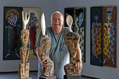 Der Chemnitzer Klaus Süß mit den Holzskulpturen, die er als Gabel-, Messer- und Löffelkopf bezeichnet. Im Hintergrund Drucke und Druckstöcke der Technik „verlorene Form“.