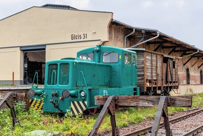 Der ehemalige Güterschuppen, der heute die Oldtimer-Garage beherbergt. Rangierdiesellok V 10 und Güterwaggon sind eine Reminiszenz an den einst bedeutenden Bahnknoten Falkenstein. 