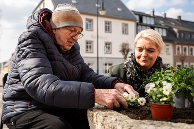 Bei Sonnenschein pflanzt Lysann Wanke, Leiterin der sozialen Betreuung im Pflegeheim „Am Wallgraben‘‘ in Sayda, gemeinsam mit Bewohner Lothar Schulz vor dem Rathaus Vergissmeinnicht ein.