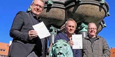 Freibergs OB Sven Krüger verpasst Keimzeit-Frontmann Norbert Leisegang und Kai Suttner, künstlerischer Leiter des Tivoli (von links) "Strafzettel" für den verbotenen Ritt auf dem Löwen des Otto-Brunnens. 