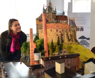 Burgverwalterin Susanne Tiesler in der aktuellen Ausstellung "Dicke Luft. Burg Kriebstein und die Papierfabrik 1856-1945",hier das von Andreas Funke gebaute Modell. 