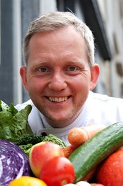Robert Beck, Koch im vegetarischen Restaurant "Hiller", sitzt im September 2012 in Hannover an einem Tisch voll Gemüse vor dem Restaurant.