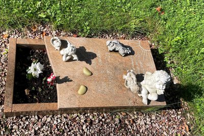 Die durchnässten und unansehnlichen Plüschtiere sind  im Frühjahr von den Friedhofsgärtnern entfernt worden. Doch inzwischen sitzen fünf kleine Engel auf der Grabplatte.