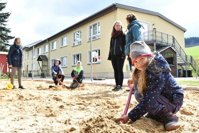 Die Hortkinder, im Vordergrund Hanna, nutzen ebenso wie die jüngeren Mädchen und Jungen ihren neuen Sandkasten fast täglich. Im Hintergrund die Erzieherinnen Jutta Wieczorek, Celine Böhme und Kitaleiterin Anke Baumgartner (h. v. l.)
