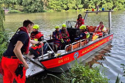 Einsatzkräfte der Wasserwacht des Deutschen Roten Kreuzes (DRK) mit einem Mehrzweckboot auf dem Chemnitzer Schloßteich.