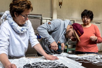 Für den Konstrukteur Kevin Päßler war dieser Freitag ein besonderer Arbeitstag. Der junge Mann ging den Klöpplerinnen Steffi Schneider (l.) und Ilona Meyer tatkräftig und versiert mit dem Akkubohrer zur Hand.