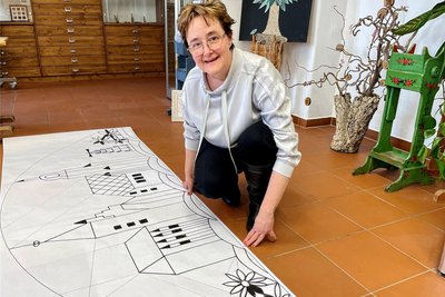Steffi Schneider zeigt den überdimensionalen Klöppelbrief, der auf keinen herkömmlichen Klöppelsack passt.