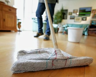 Eine Reinigungskraft putzt mit einem sogenannten Aufnehmer den Boden. Im Vogtlandkreis sollten Aufträge für sieben Schulen vergeben werden. Doch die Verwaltungsvorlage ist fehlerhaft.