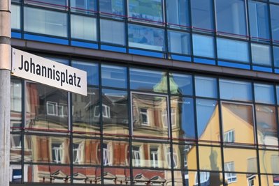 Häuser am Johannisplatz in Limbach-Oberfrohna spiegeln sich in einer Glasfassade. Die Stadt will ihr Zentrum mit verschiedenen Ideen auch mit Blick auf das Kulturhauptstadtjahr 2025 in Chemnitz weiter aufwerten. 
