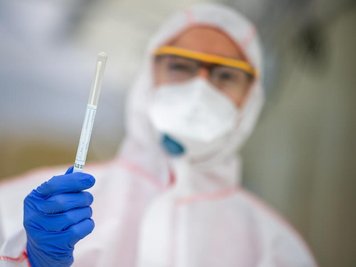            Ein Mitarbeiter hält in einem Abstrichzentrum einen Coronatest-Abstrich in der Hand.