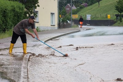 Ein Anwohner von Sachsenburg versucht mit einem Besen den Gully frei zu halten.