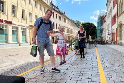 Melina (4) aus Halsbrücke testet die Slackline auf der Petersstraße mit ihrem Papa Sebastian Hertwig. Auch ihr Bruder Leon (2) ist neugierig und balanciert an den Händen von Mama Isabel .