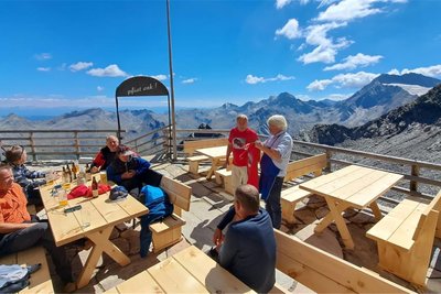 Auf der mit neuen Holztischen und -bänken ausgestatteten Terrasse der Zwickauer Hütte vor dem herrlichen Alpenpanorama.