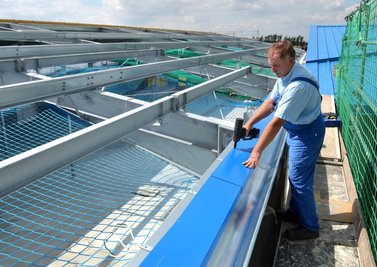 Wolfgang Wunderlich, Mitarbeiter der Firma Leuteritz Anlagenbau, befestigt gerade ein blaues Blech auf dem neuen Hallendach.