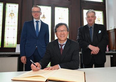 Prof. Dr. Jhy-Wey Shieh (Mitte) beim Eintragen ins Ehrenbuch der Stadt Aue-Bad Schlema im Juli 2021. Im Hintergrund stehen der ehemalige CDU-Bundestagsabgeordnete Alexander Krauß (l.) und der ehemalige Oberbürgermeister von Aue-Bad Schlema, Heinrich Kohl (CDU).