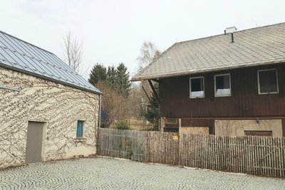 Das holzummantelte Haus grenzt unmittelbar an die Kulturscheune.