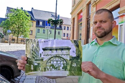 Torsten Eismann zeigt ein Foto des Stadttores, das im Jahr 1930 das damalige Meeraner Heimatfest zierte.