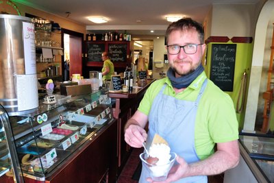 Im Café Flora in Mulda kredenzt Inhaber David Liebig gerade einen Eisbecher mit gemischtem Eis.