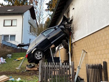 Ein Auto steckt nach einem schweren Unfall in einer Hauswand. Der Autofahrer starb, die Hausbwohner blieben äußerlich unverletzt, wie die Polizei mitteilte. Sie erlitten allerdings einen Schock. Warum der Wagen am Sonntag von der Straße abkam, war noch unklar. 