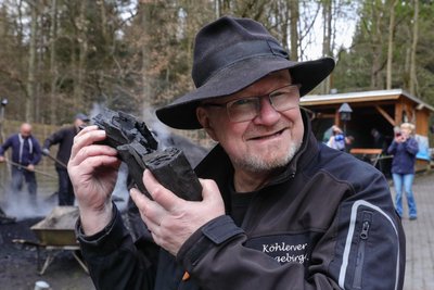 Hobbyköhler Heiko Schmidt lobt die Qualität der Holzkohle. Er hört es am Klang.