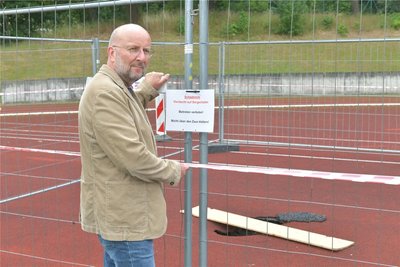 Dierk Schülke von der Stadtverwaltung Brand-Erbisdorf kontrollierte am Freitag die Absperrung auf dem Sportplatzgelände an der Dammstraße. Im Tartanbelag hat sich ein tiefes Loch aufgetan.