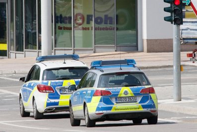 Ein Mann wird in Handschellen abgeführt und in einem Streifenwagen aufs Polizeirevier gebracht.