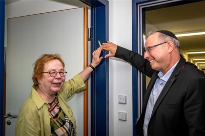 Ruth Röcher und Rabbi Dannyel Morag befestigen eine Mesusa an einem Türrahmen.