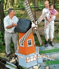 Diese Windmühle ist eines der größten Modelle in der "Rentnersruh". Gebaut wurde sie 1968 von Herbert Preiß. Heinz Hahn (links) stellt sie dem ehemaligen Meinersdorfer Heiko Scholz mit Tochter Vanessa vor.