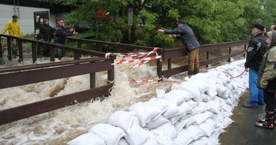 Gefahr im Verzug: An der Brücke staute sich das Pöhlwasser, flutete die Straße und suchte seinen Weg auf die angrenzenden Grundstücke. Sandsäcke sollten das verhindern. In der Nacht waren die Felder aus dem Brückengeländer herausgesägt worden, am Tag wurde das Geländer ganz entfernt.