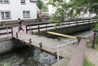 Der Bach hat sich wieder beruhigt, die Fußgängerbrücke ist aus Sicherheitsgründen gesperrt. Ob sie wie angekündigt abgerissen werden soll, darüber gehen die Meinungen im Ort auseinander - je nach Betroffenheit. Fragen gibt es auch zu den zwei Rohren, die hier den Bachlauf queren.