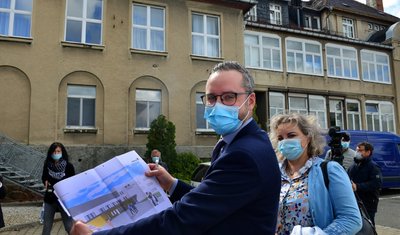 Der Altbau im Hintergrund wird abgerissen. LMK-Geschäftsführer Florian Claus zeigt, wie der Neubau, der an jener Stelle hochgezogen wird und in dem auch die stationäre Notfallversorgung zu finden sein wird, einmal aussehen soll.