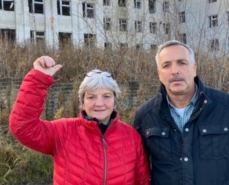 Gabi und Achim Döbrich vor einem zerstörten Haus in einem der Orte in der Ostukraine. 