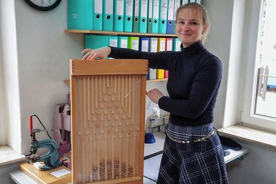 Peggy Höhne mit einem Galtonbrett: Wenn die Holzkugeln durch den Apparat rollen, bilden sie unten eine Gauß'sche Kurve.