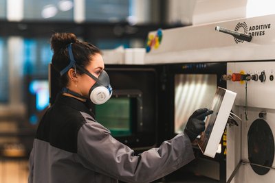 Motorteile auf Knopfdruck von Additive Drive, einer preisgekrönten Ausgründung der Bergakademie: Entwicklungsingenieurin Annalena Held bedient einen industriellen 3D-Drucker.