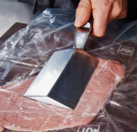 Mit dem Plattiereisen wird das Fleisch flach geklopft.