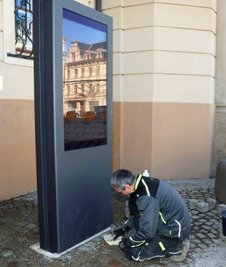 Ein Bauarbeiter bei letzten Arbeiten an der Informationstafel neben dem Rathauseingang. 