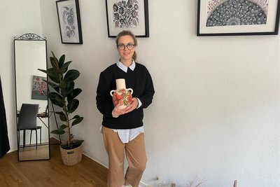 Künstlerin Olena Grishyna aus der Ukraine zeigt eine Vase, die sie mit Petrykiwka-Malerei gestaltet hat.
