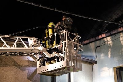 Feuerwehrmann und Schornsteinfeger im Drehleiterkorb der Feuerwehr Aue, kurz vor der Reinigung des in Brand geratenen Schornsteins.