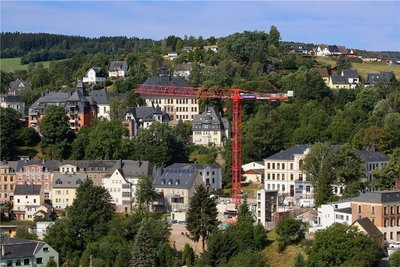 Ein Teleobjektiv macht's möglich: Beim Blick aus dem Schwarzenberger Schloss zum Becherberg scheint die Baustelle des altstadtnahen Parkhauses an der Erlaer Straße zum Greifen nah. Nachdem erst ein Autodrehkran den Bauleuten bei der Montage half, beherrscht jetzt ein riesiger Turmdrehkran die Baustelle. Rechts von ihm ist schon das Treppenhaus zu sehen. Der Bau kostet die Stadt etwa 4,3 Millionen Euro. Das sieben Ebenen umfassende Parkhaus soll 163 Stellplätze bieten und ab dem diesjährigen Weihnachtsmarkt nutzbar sein. stl 