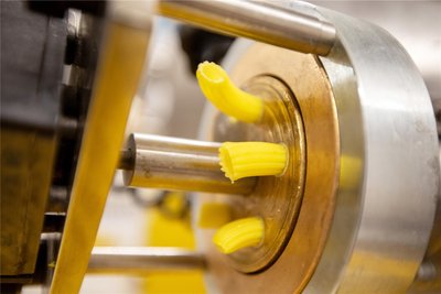 In der Nudelmaschine wird der Teig durch eine Bronzematritze gepresst - so entstehen die charakteristischen Pastaformen.